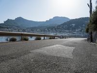 paved road in front of water with mountains in background and boat launch at right corner