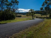 a paved roadway in the country side with mountains in the distance and a road at the end