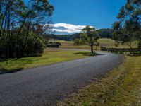 a paved roadway in the country side with mountains in the distance and a road at the end