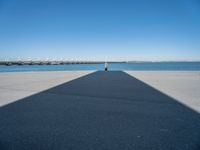 a pier with a long shadow casting a long line across it's water and bridge