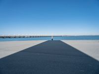 a pier with a long shadow casting a long line across it's water and bridge