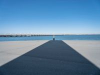 a pier with a long shadow casting a long line across it's water and bridge