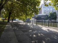 a scenic river path along an urban waterfront with buildings in the background and tree lined streets