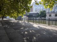 a scenic river path along an urban waterfront with buildings in the background and tree lined streets