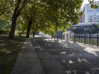 a scenic river path along an urban waterfront with buildings in the background and tree lined streets