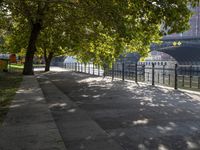 a scenic river path along an urban waterfront with buildings in the background and tree lined streets