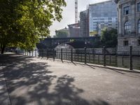 a scenic river path along an urban waterfront with buildings in the background and tree lined streets