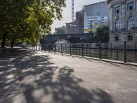 a scenic river path along an urban waterfront with buildings in the background and tree lined streets