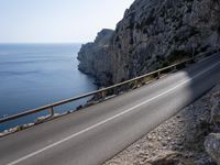 a motorcycle is parked on the road near the ocean and mountainside in turkey on an autumn day