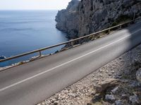 a motorcycle is parked on the road near the ocean and mountainside in turkey on an autumn day