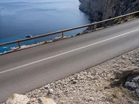 a motorcycle is parked on the road near the ocean and mountainside in turkey on an autumn day