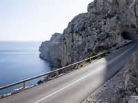 a motorcycle is parked on the road near the ocean and mountainside in turkey on an autumn day