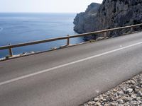 a motorcycle is parked on the road near the ocean and mountainside in turkey on an autumn day