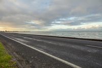 there is a water view along the road, along with a sea, grass and clouds