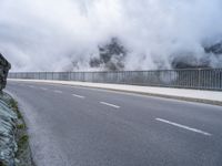 a road and a cliff on a cloudy day, with a steam - powered structure in the background