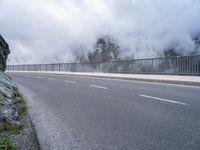 a road and a cliff on a cloudy day, with a steam - powered structure in the background