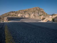 a mountain view of a road with a yellow line on the side of it and some rocks in front of it