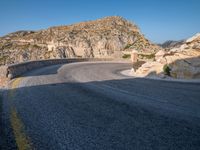 a mountain view of a road with a yellow line on the side of it and some rocks in front of it