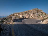 a mountain view of a road with a yellow line on the side of it and some rocks in front of it