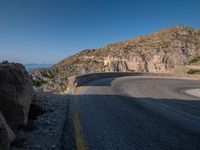 a mountain view of a road with a yellow line on the side of it and some rocks in front of it