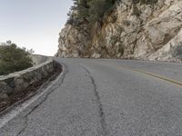 the road has a paved curve and there is mountains in the background on both sides