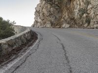 the road has a paved curve and there is mountains in the background on both sides