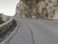 the road has a paved curve and there is mountains in the background on both sides