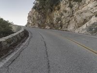 the road has a paved curve and there is mountains in the background on both sides