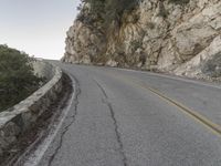 the road has a paved curve and there is mountains in the background on both sides