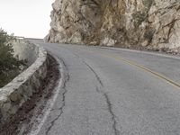 the road has a paved curve and there is mountains in the background on both sides