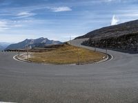 a curved road in the middle of the mountains with cows grazing beside it on the side of the road