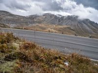 a person rides their bicycle along a winding road through mountains under cloudy skies and fluffy clouds