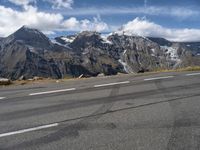 a road with white lines on it and mountains behind it in the distance, snow capped mountain range