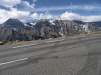 a road with white lines on it and mountains behind it in the distance, snow capped mountain range