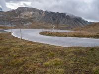 a view of the road to the mountains from behind it and below, with two poles, power lines, and grass