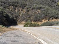 a very long empty road with trees and hills in the background taken from the ground