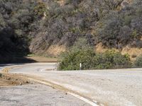 a very long empty road with trees and hills in the background taken from the ground