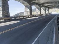 a bike is riding on the curved section of the highway in a tunnel, underneath the bridge