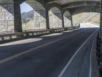 a bike is riding on the curved section of the highway in a tunnel, underneath the bridge