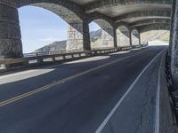 a bike is riding on the curved section of the highway in a tunnel, underneath the bridge