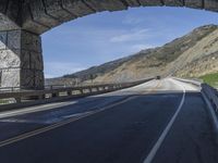 a bike is riding on the curved section of the highway in a tunnel, underneath the bridge