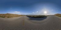 a 360 - view photo of the sky, ground and the road in the center of the picture