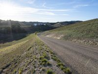 a dirt road near some green grass on the side of a hill with some houses