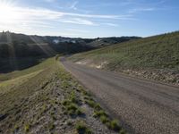 a dirt road near some green grass on the side of a hill with some houses