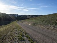 a dirt road near some green grass on the side of a hill with some houses