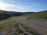 a dirt road near some green grass on the side of a hill with some houses