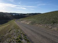 a dirt road near some green grass on the side of a hill with some houses