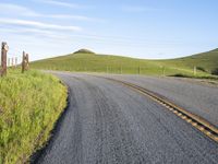 the road stretches along the hill side to the distant hills, with yellow stripes on the edge