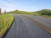 the road stretches along the hill side to the distant hills, with yellow stripes on the edge