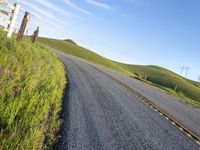 the road stretches along the hill side to the distant hills, with yellow stripes on the edge